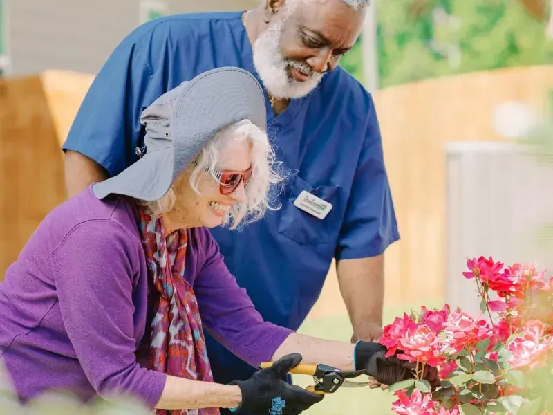 A caregiver helping a smiling client arrange flowers